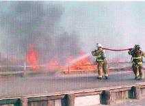 Asst Chief Bailey and a Firefighter using the 'over the shoulder' method to suppress the fire in the dunes along First Avenue